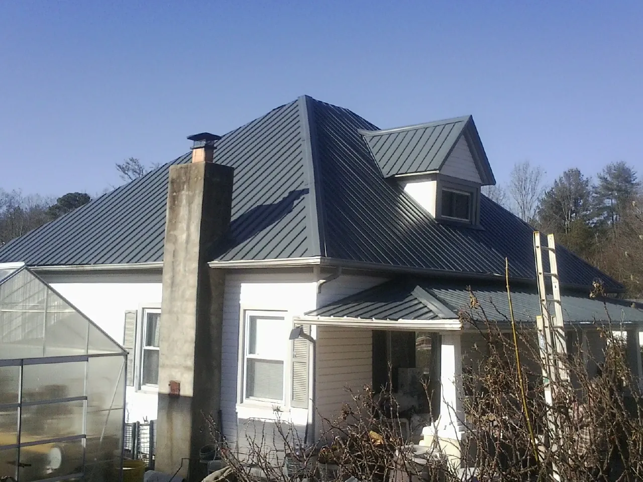 Dark blue standing seam metal roof on a white farmhouse with dormer — Slate & Tile Roof Repair by Roofing Brothers in Upperville