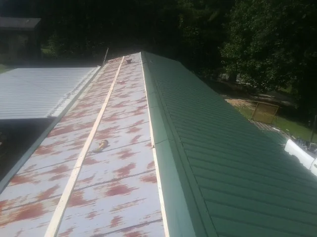 Old rusted panels beside newly installed green metal roofing — Wind Damage Roof Repair by Roofing Brothers in Upperville