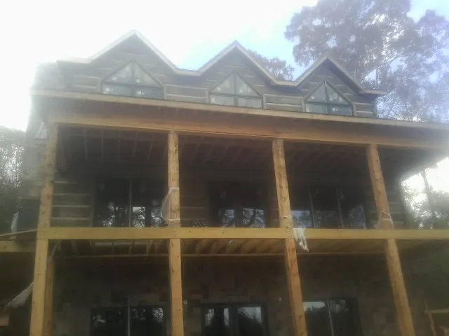 Dormers and porch framing on a large log home under construction — Roof Coating work by our crew in Upperville