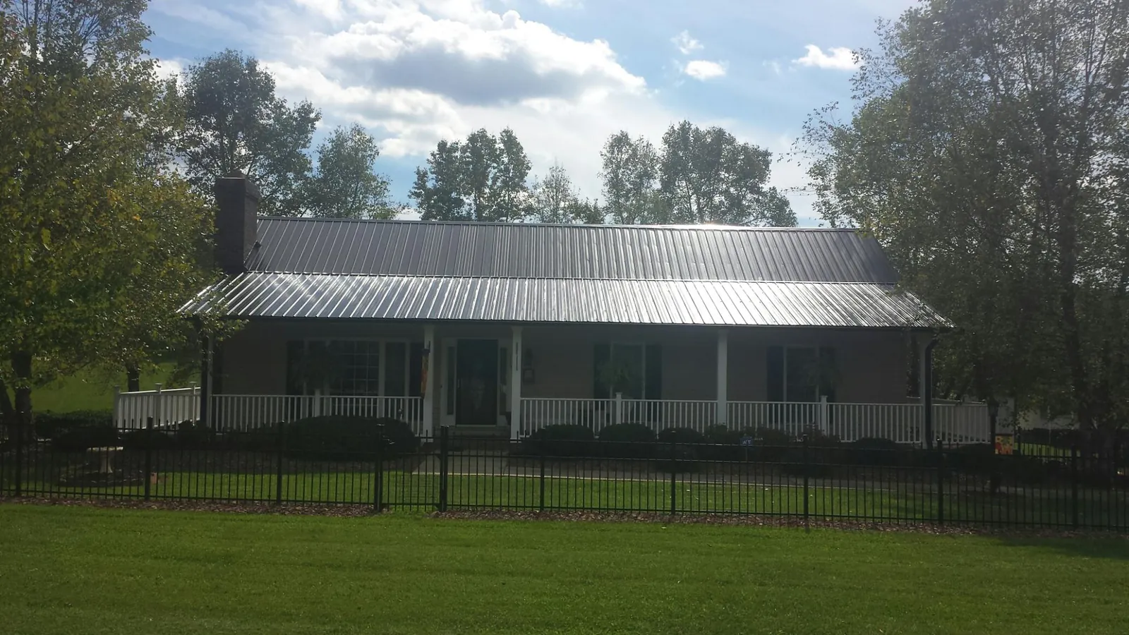 Gray metal roof on a brick ranch with a full width front porch — Gutter Guard Installation work by our crew in Upperville