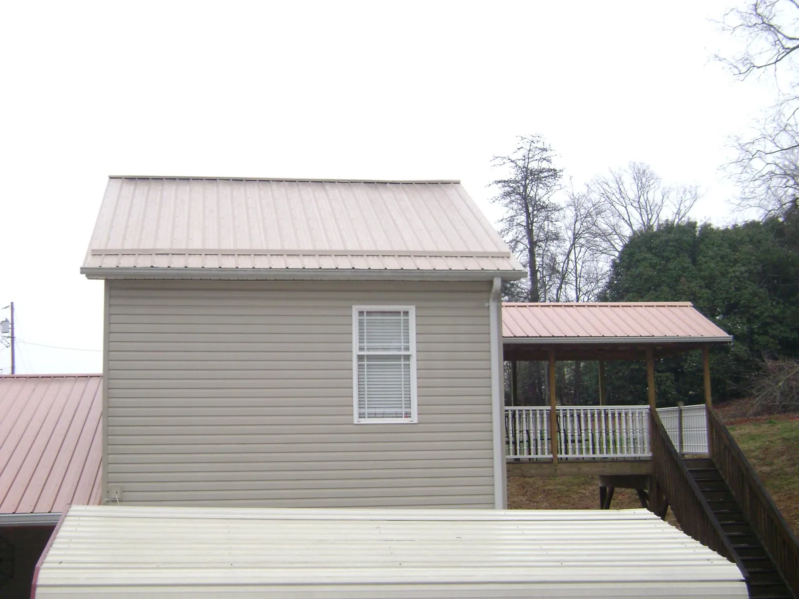 Tan metal roofs on a two story addition and attached porch, from a Roof Replacement job in Upperville